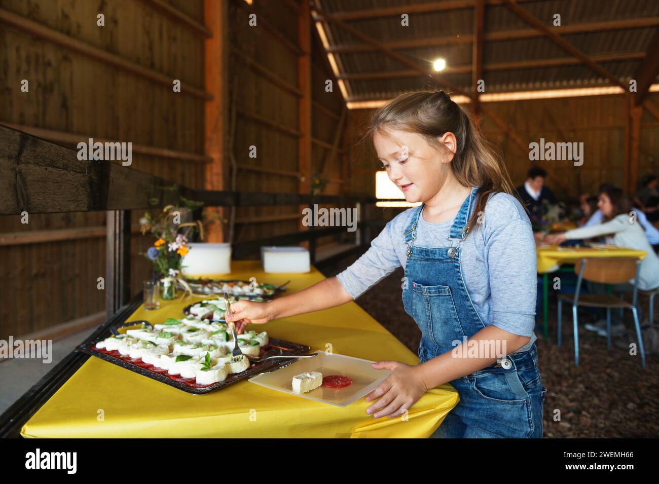 Bambina che si serve formaggio fresco di mucca, snack salutare, festa in stile fattoria Foto Stock