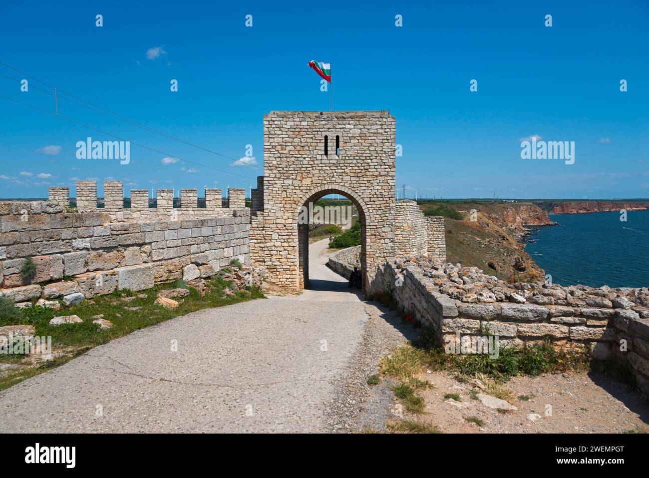 Mura della fortezza in pietra con ingresso alla galleria e bandiera sventolante in una giornata di sole, rovine della fortezza, Capo Kaliakra, Dobruja, Mar Nero, Bulgaria Foto Stock