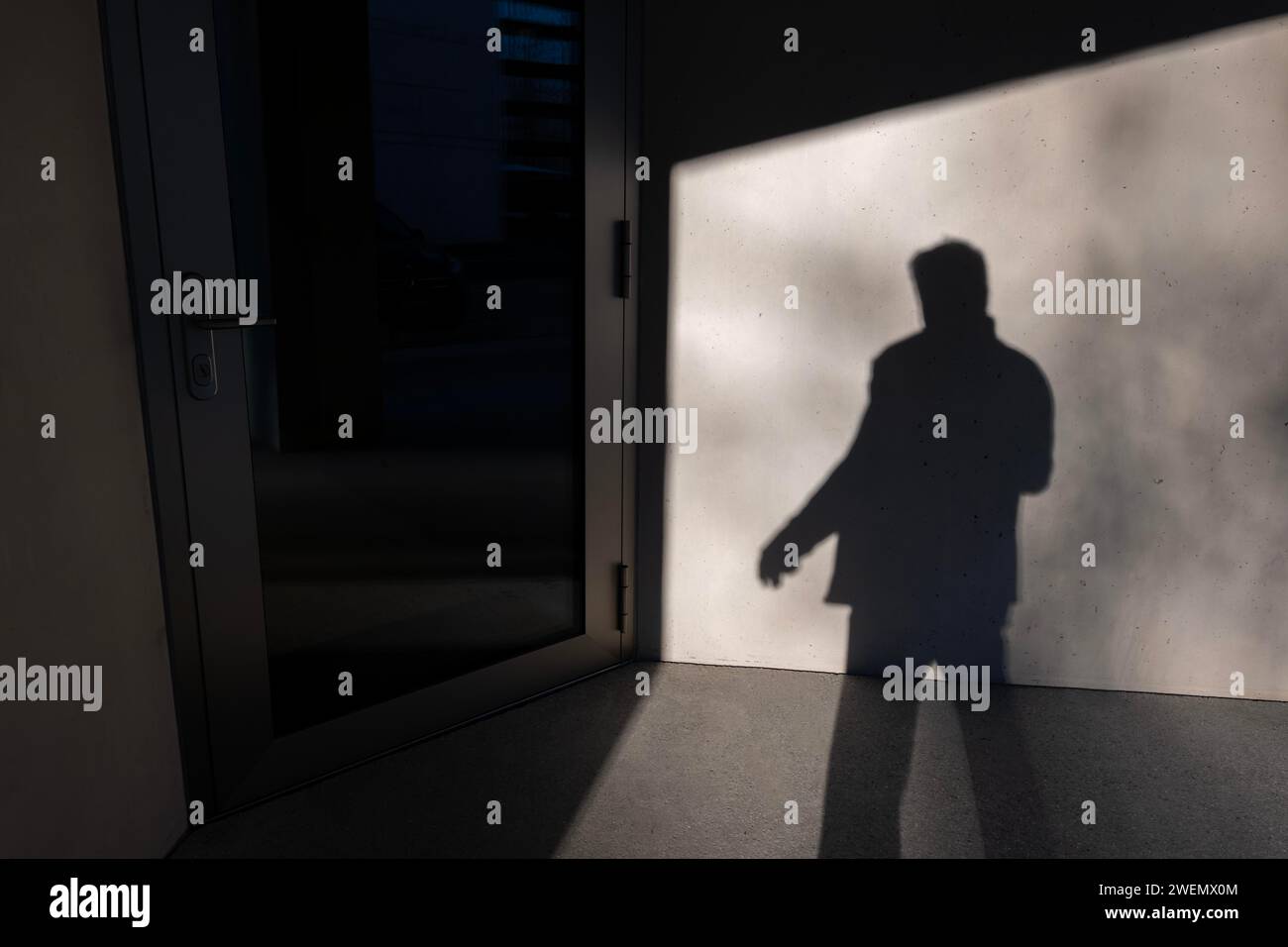 Shadow of a Man on the concrete Wall ed entrare in una porta d'ufficio in una giornata di sole in Svizzera Foto Stock