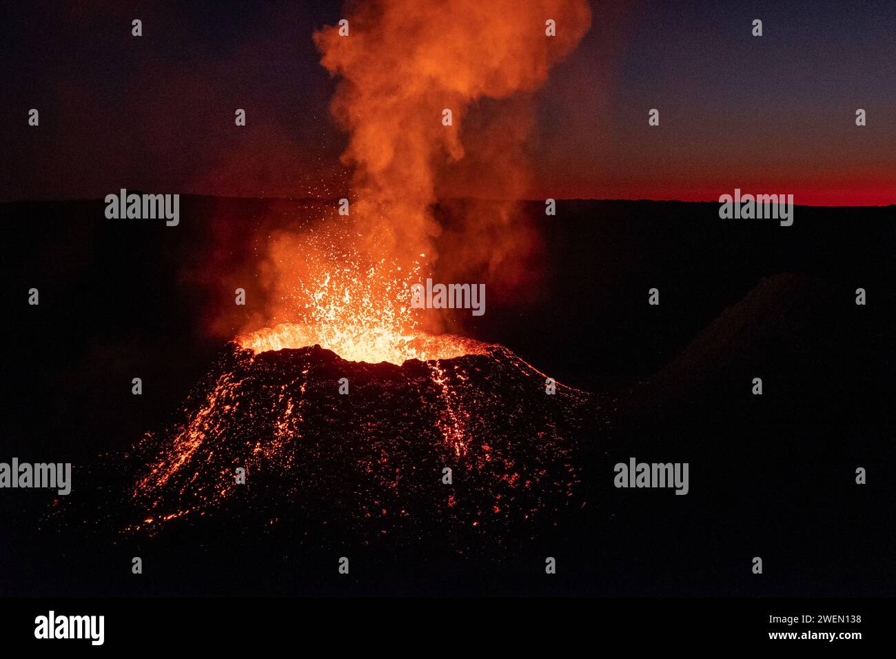 Il vulcano Piton de la Fournaise erutta sull'isola di Reunion, sparando ruscelli di lava fusa in alto nell'aria sotto la copertura dell'oscurità. Foto Stock