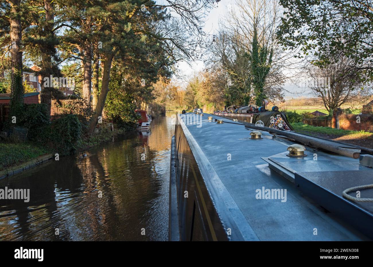 Vista da un narrowboat che viaggia nel paesaggio urbano della campagna inglese sul canale navigabile britannico attraverso il villaggio Foto Stock