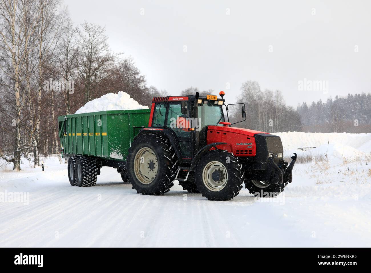Il trattore Red Valtra Valmet 8550 trasporta il carico di neve sul rimorchio sgombra dalle strade all'area di scarico della neve municipale. Salo, Finlandia. 19 gennaio 2024. Foto Stock