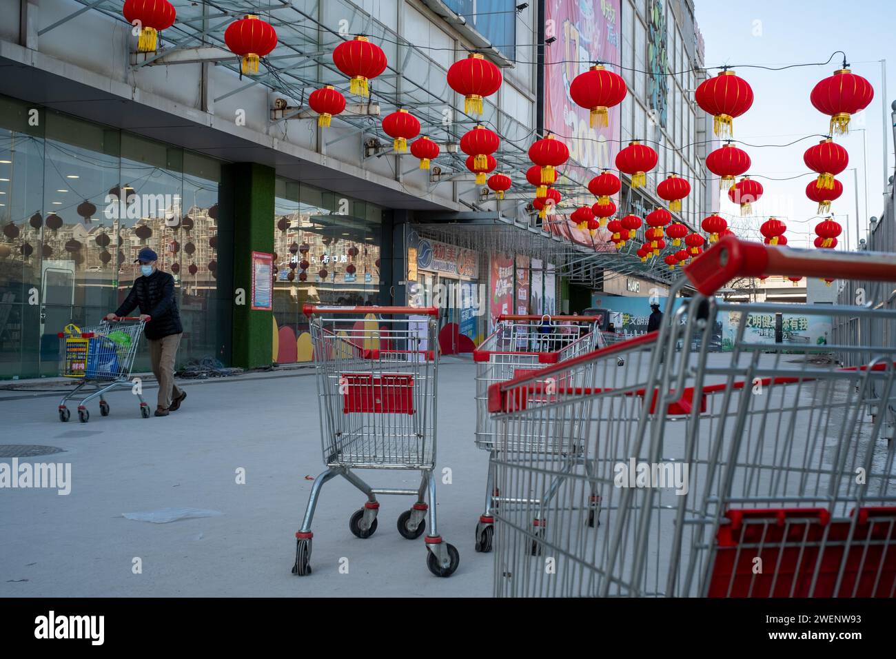 I consumatori lasciano un centro commerciale decorato con lanterne rosse dopo lo shopping mentre il Festival di Primavera Cinese si avvicina a Pechino. 01-gen-2024 Foto Stock