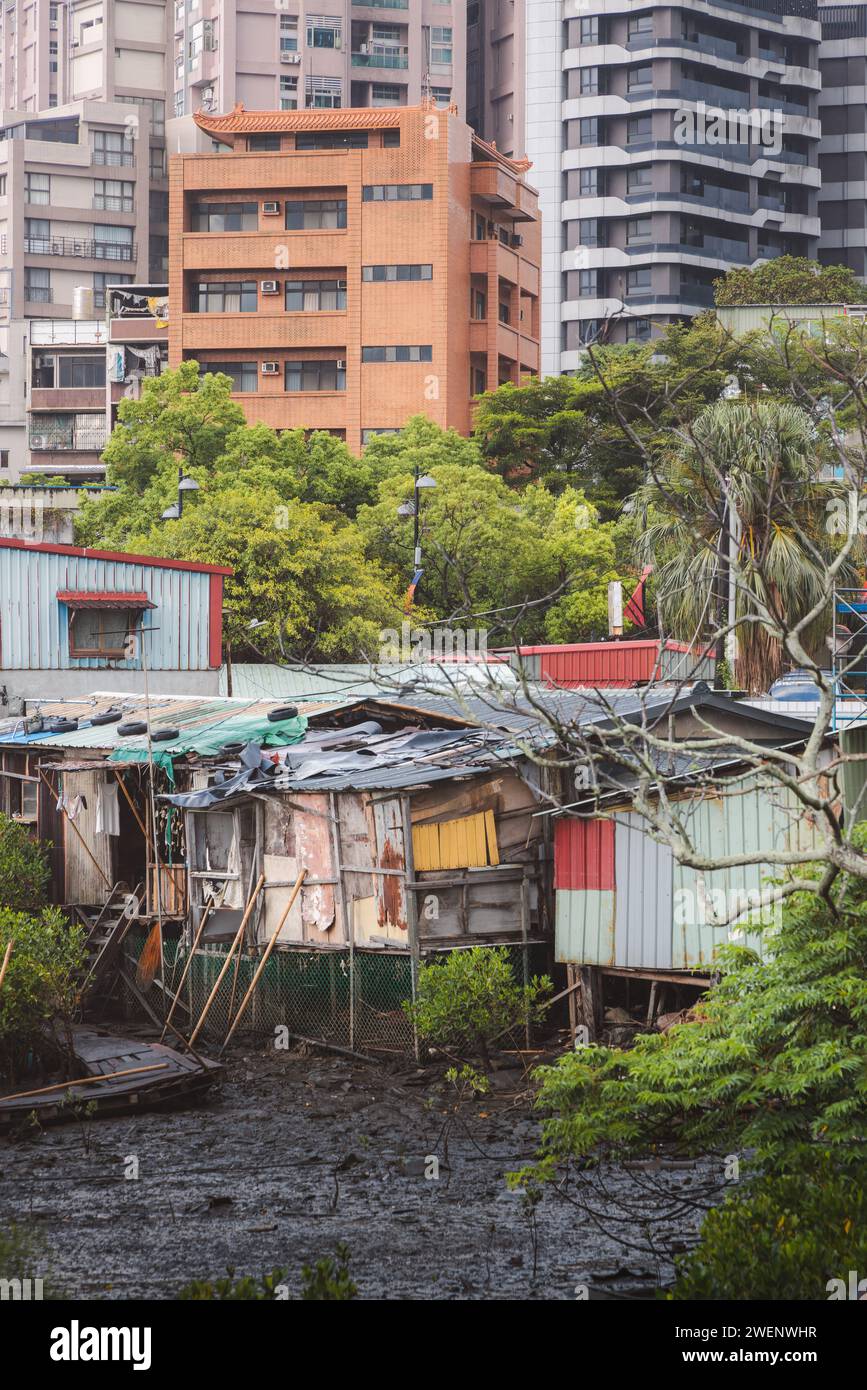 Esempio di gentrificazione con povera palafitta nel fango contrastava con gli edifici più moderni del distretto di Tamsui, Taipei, Taiwan. Foto Stock