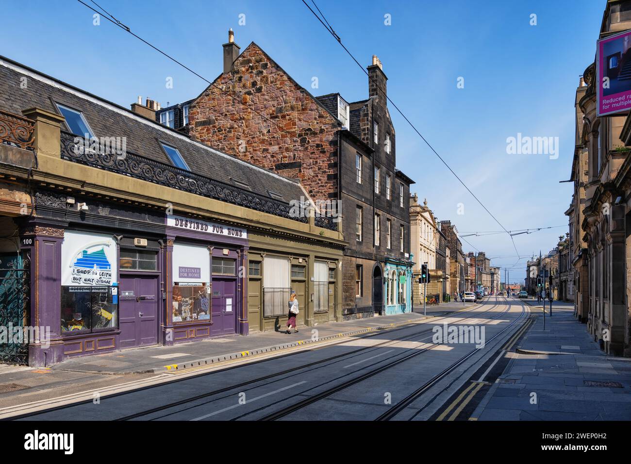 Constitution Street nel quartiere Leith, Edimburgo, Scozia, Regno Unito. Strada principale con tram, destinata al negozio di articoli da regalo Home sulla sinistra. Foto Stock