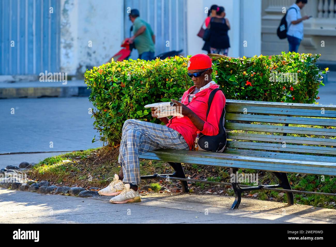 Uomo di etnia afro caraibica che legge un giornale nel parco Leoncio Vidal a Santa Clara, Cuba Foto Stock