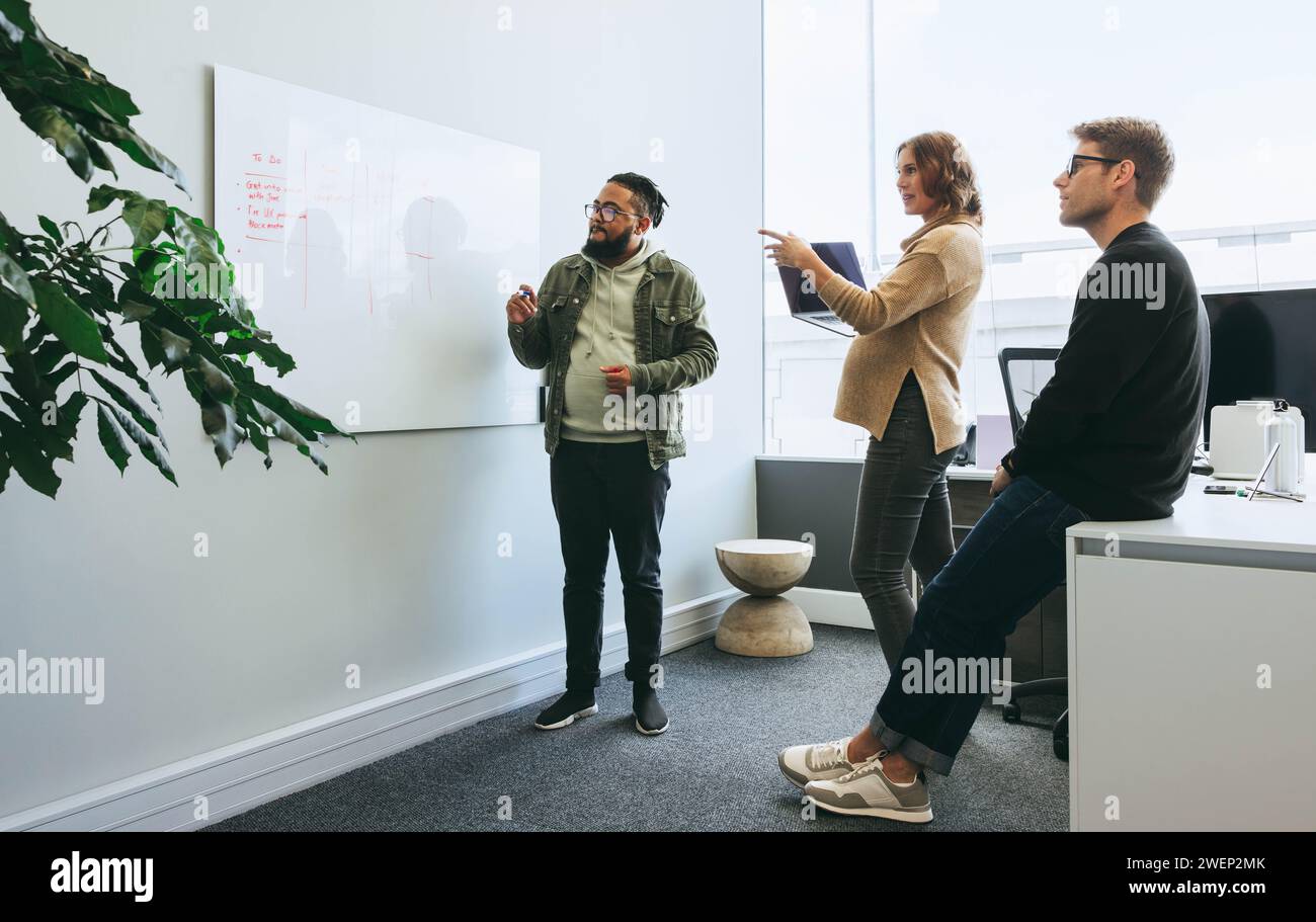 In un ambiente di ufficio, i professionisti si impegnano in discussioni collaborative. uomini d'affari e donne d'affari discutono idee, sottolineando il lavoro di squadra, il progetto Foto Stock