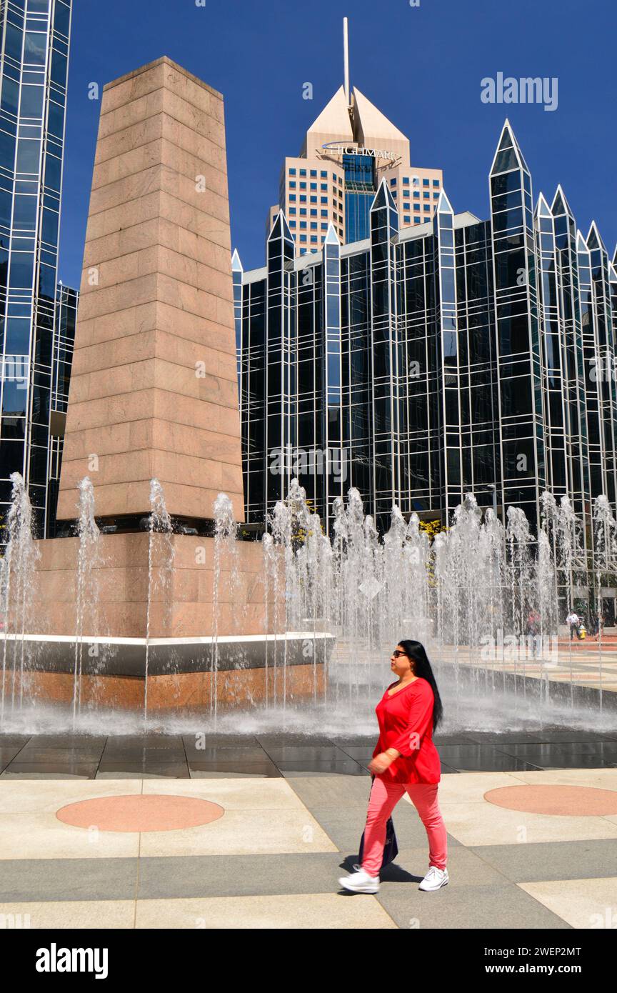 Una donna adulta cammina intorno alle fontane e all'obelisco di PPG Place nel centro di Pittsburgh, Pennsylvania, durante una pausa pranzo Foto Stock