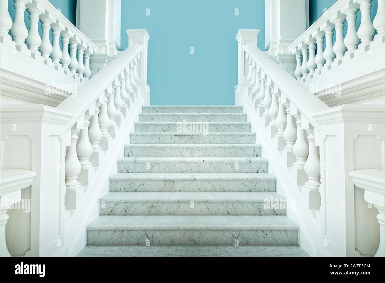 Elegante scala simmetrica bianca con parete blu dietro Foto Stock