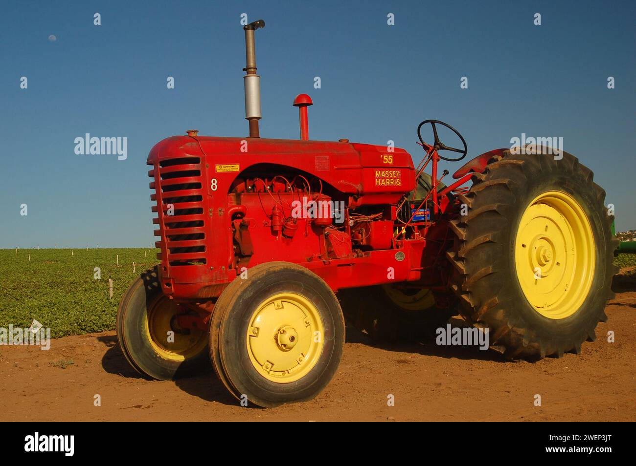 Un trattore rosso e giallo d'epoca è parcheggiato vicino ai prati e ai campi di fiori di Carlsbad, California Foto Stock