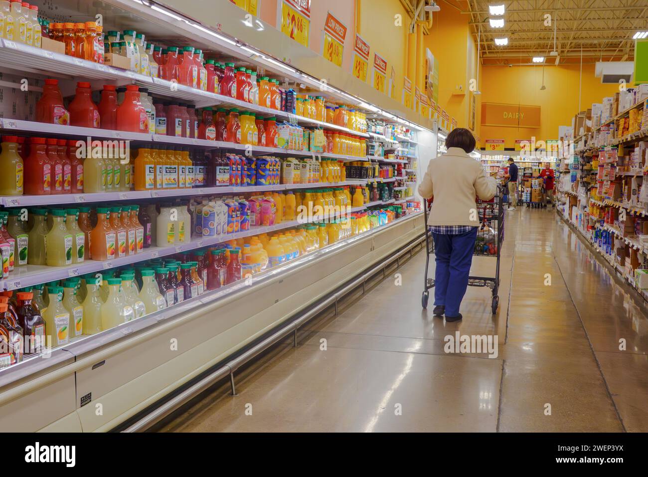 Donne anziane con carrello che camminano accanto al negozio di alimentari, frigorifero pieno di vari succhi di frutta Foto Stock
