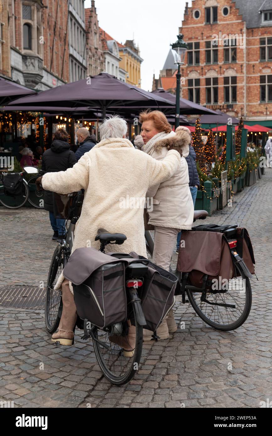 Bruges, Belgio, Europa. 21.12.2023. Donne in bicicletta un mezzo di trasporto popolare che si riunisce fuori da un ristorante nel centro di Bruges Foto Stock