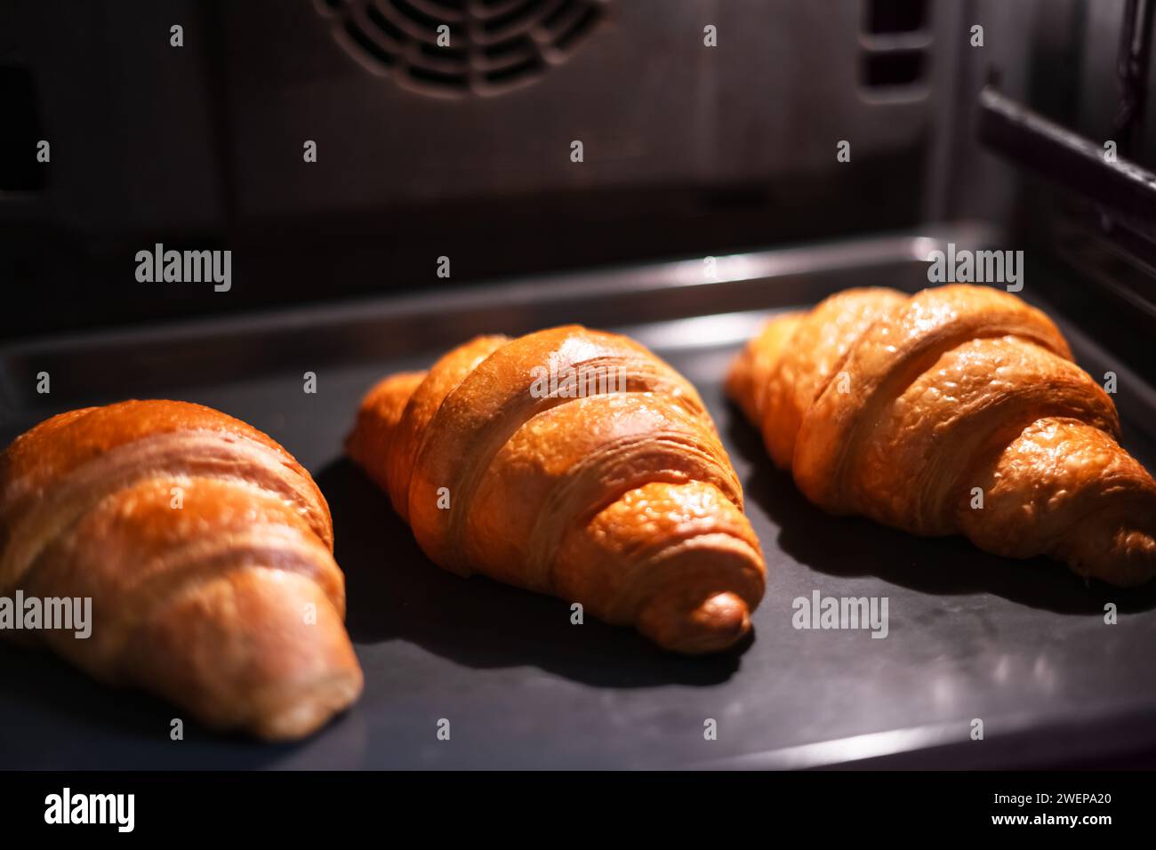 Tre croissant sono cotti nel forno domestico. Fotografia del cibo Foto Stock