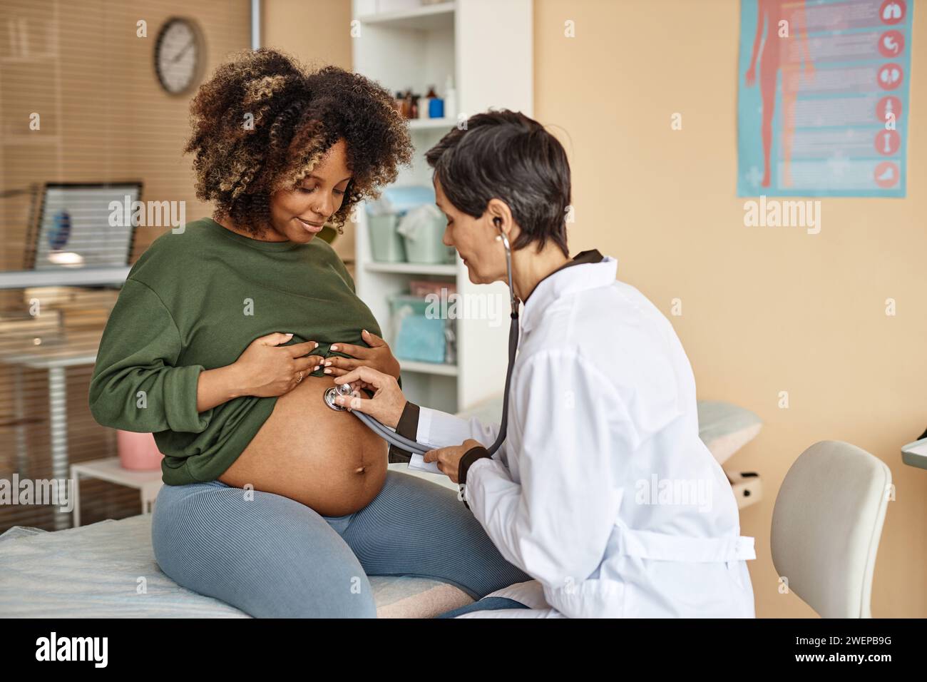 Medico che esamina una donna incinta sorridente Foto Stock