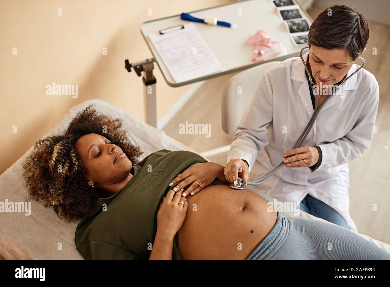 Infermiere con mamma in attesa che utilizza stetoscopio per controllare il feto Foto Stock