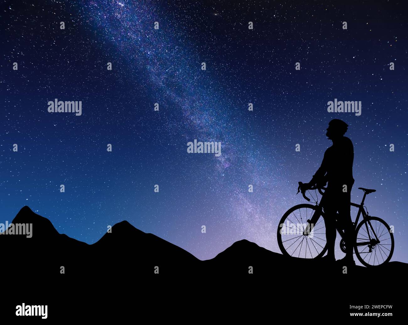 Silhouette di un ciclista sullo sfondo di montagne e cielo stellato con la via Lattea. Foto Stock