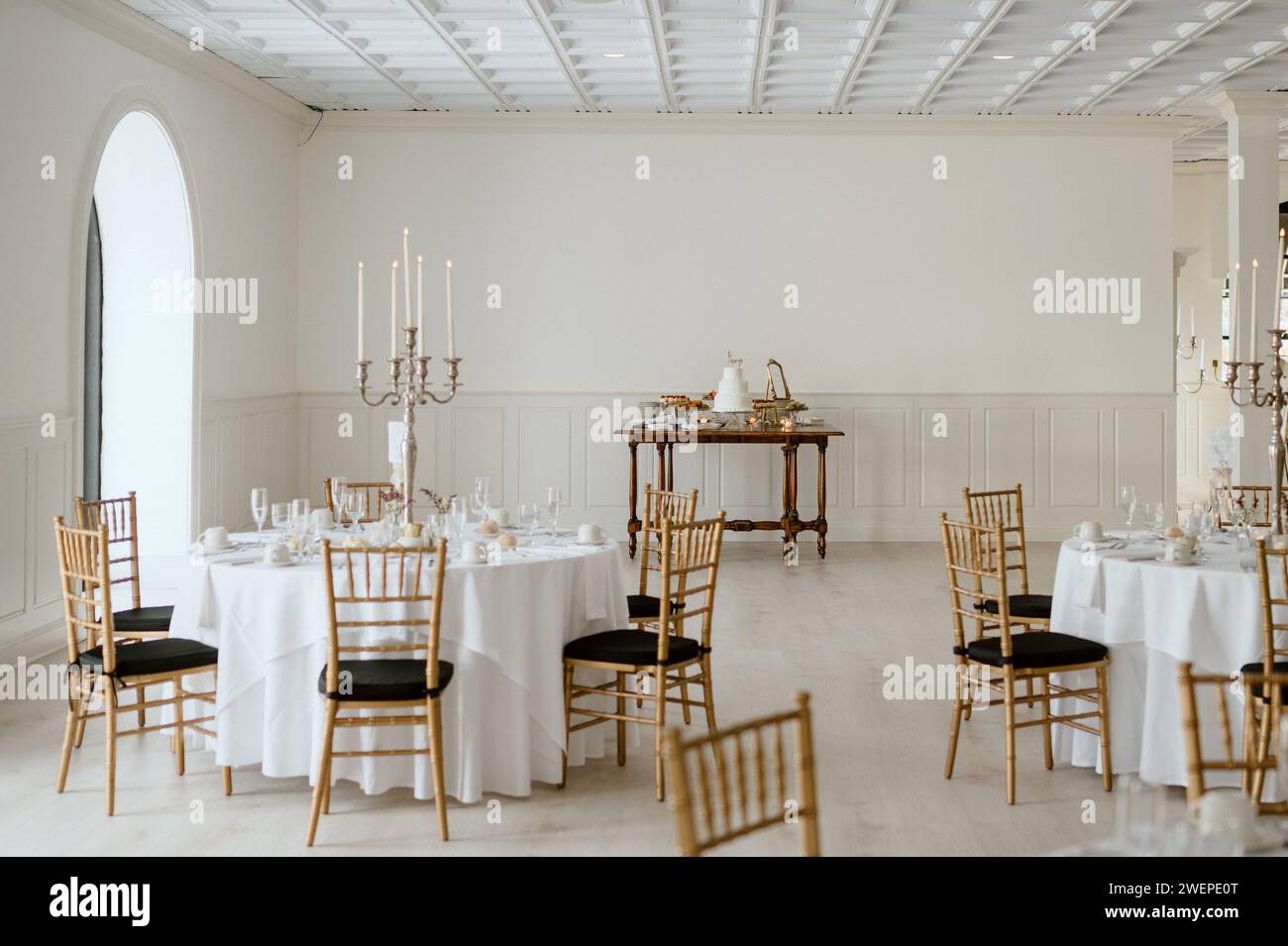 Una lunga sala con biancheria bianca, con tavoli e sedie in un moderno ambiente per matrimoni Foto Stock