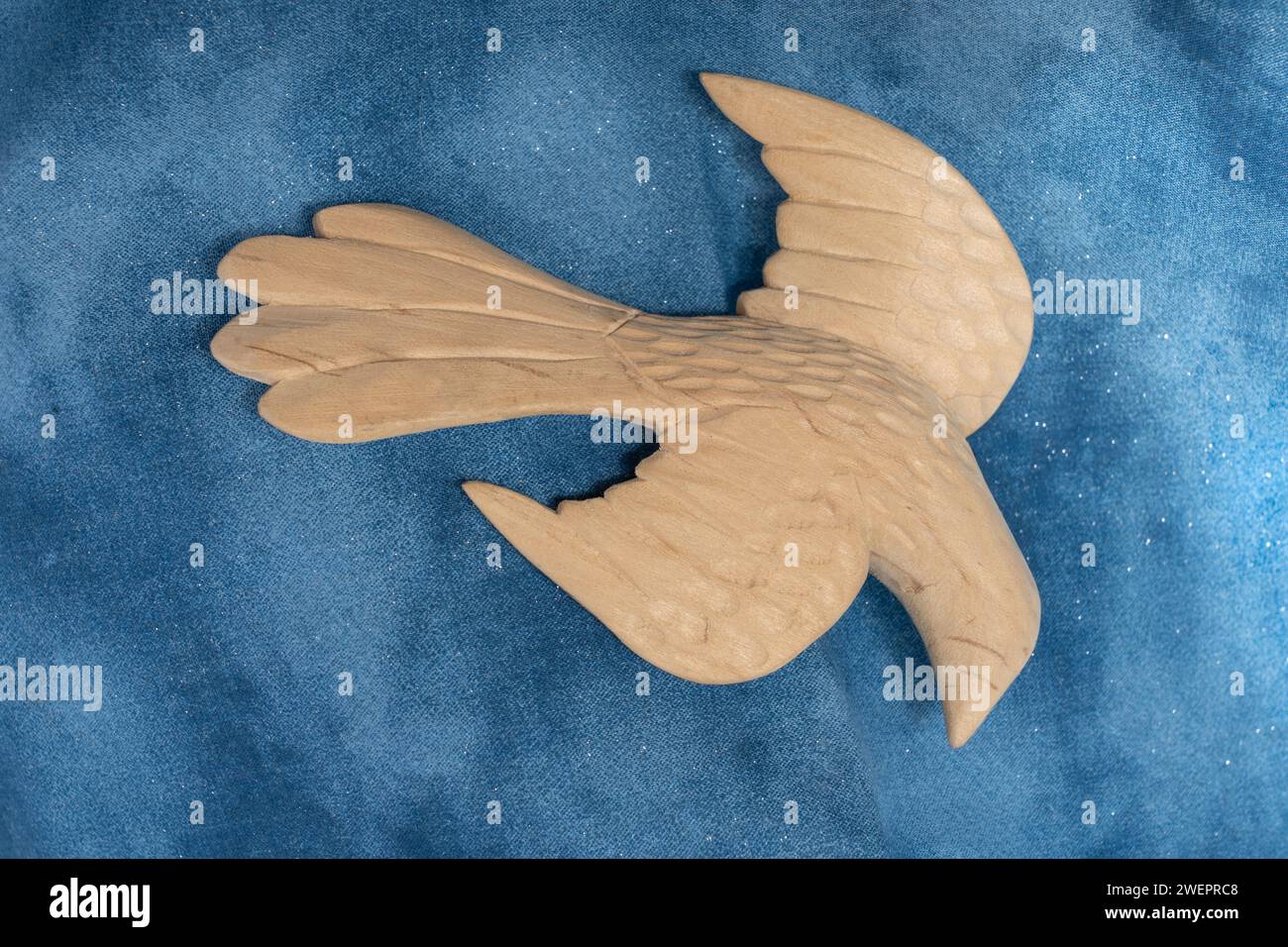 Un grande uccello a forma di colomba scolpito su tessuto blu sembra scendere in volo. Le ali sono allungate come se venissero per la pace e l'amore. Foto Stock