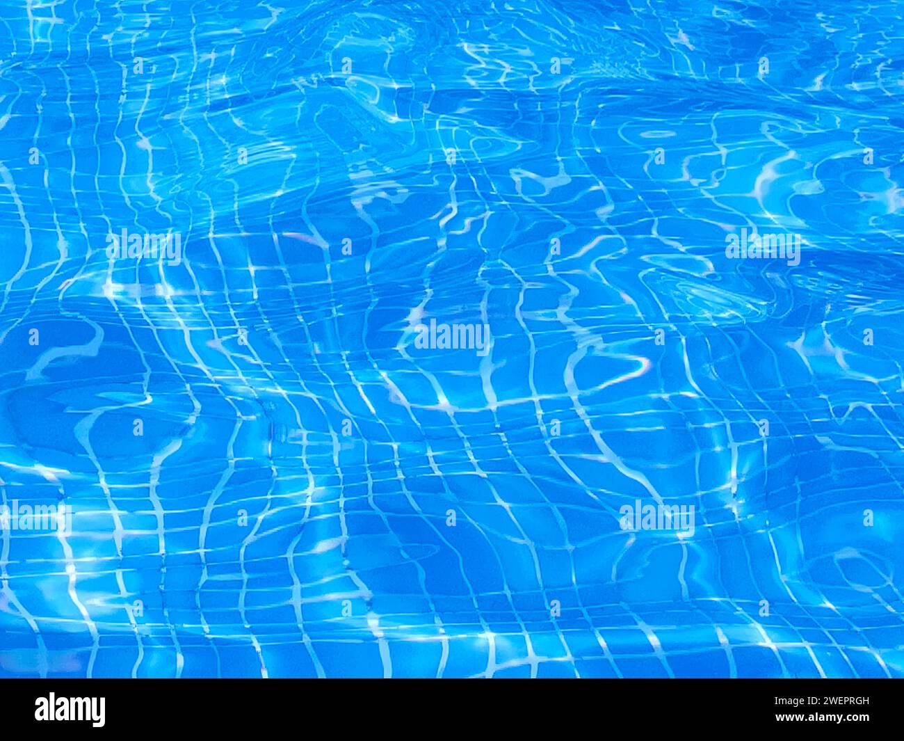 - Acqua in una piscina con i raggi del sole riflessi sulla sua superficie Foto Stock