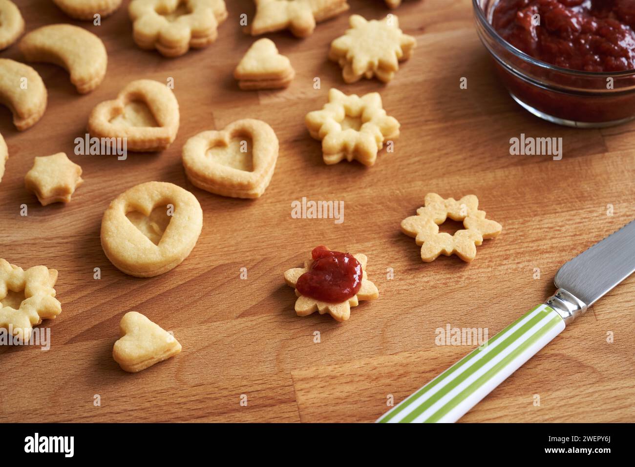 I biscotti di Natale Linzer fatti in casa vengono riempiti con marmellata di fragole su un tavolo Foto Stock