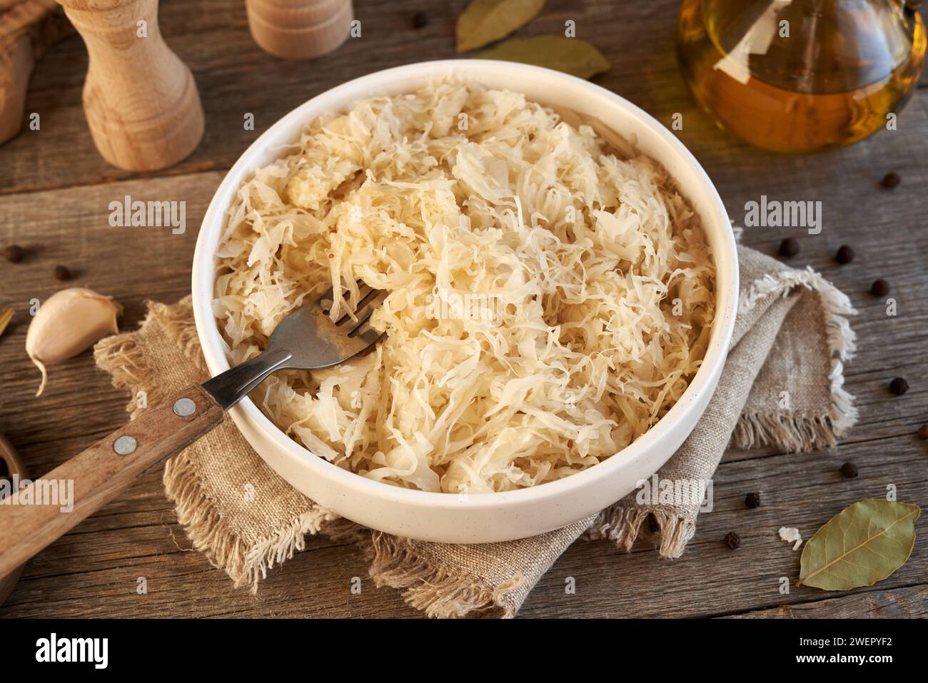 Cavolo o crauti fermentati fatti in casa in una ciotola su un tavolo di legno, con forchetta Foto Stock