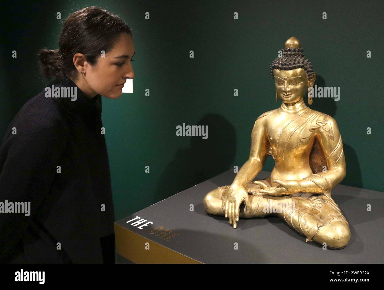 New York, New York, USA. 26 gennaio 2024. Una donna guarda una grande figura in bronzo dorato di Shakyamuni Buddha, Tibet, intorno al XIV secolo, con una stima di $ 1,8 - $ 2 milioni, visto in mostra come parte della mostra ''˜the One' durante la Masters Week tenutasi a Sotheby's New York. (Immagine di credito: © Nancy Kaszerman/ZUMA Press Wire) SOLO USO EDITORIALE! Non per USO commerciale! Foto Stock