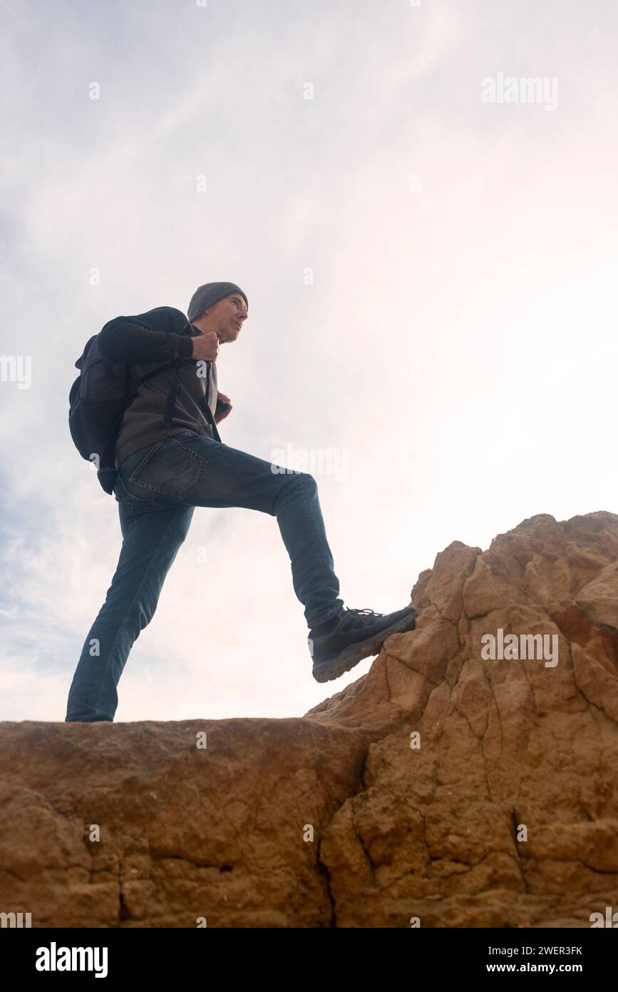 escursionista maschile con zaino che cammina sulle rocce e sale. Foto Stock