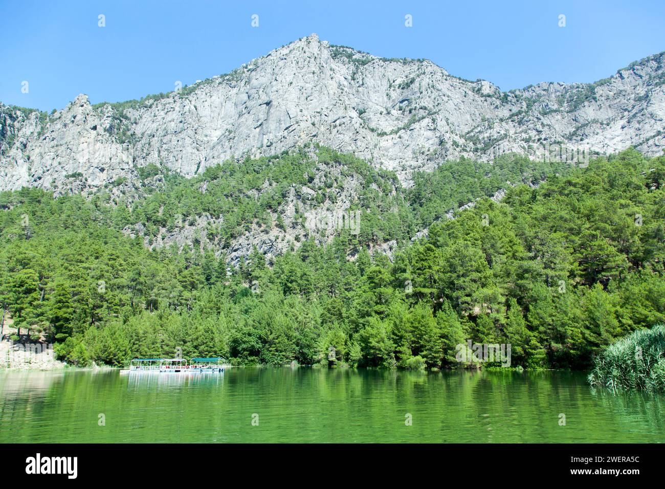 La vista panoramica del lago Karacaoren di colore verde con una piattaforma turistica e un'alta montagna rocciosa nella provincia di Antalya (Turchia). Foto Stock