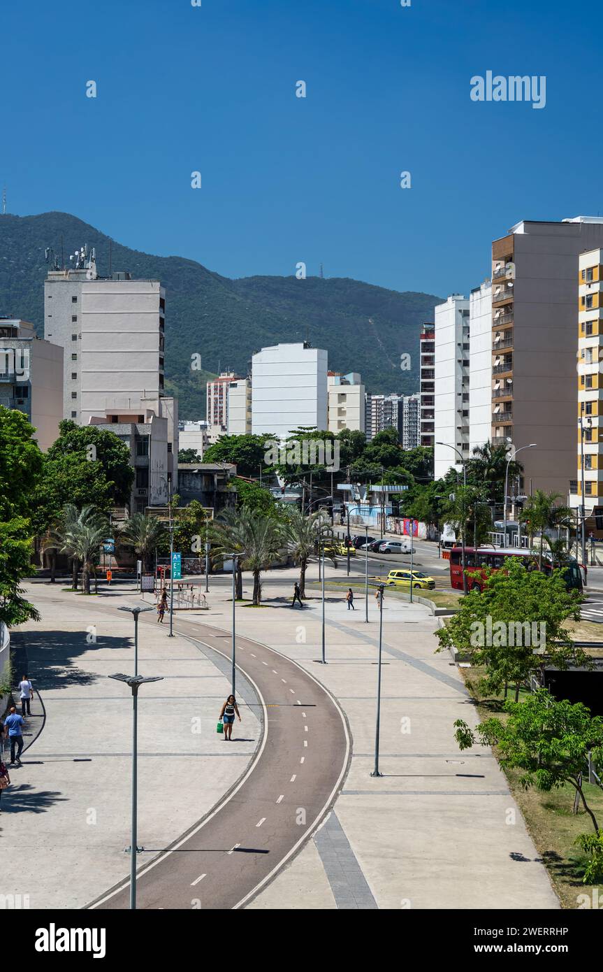Una pista ciclabile curva che corre tra lo stadio Maracana e il viale Professor Manoel de Abreu con edifici del quartiere Maracana sul retro sotto il cielo blu. Foto Stock