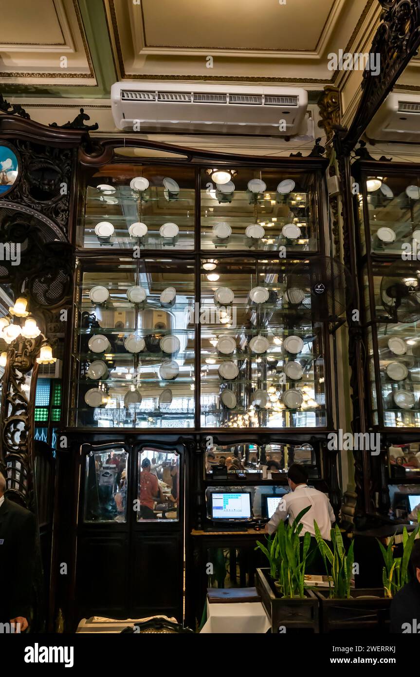 Un grande armadietto in porcellana con specchi di cristallo che espongono molti piatti in porcellana e ceramica su una delle pareti della caffetteria Confeitaria Colombo. Foto Stock