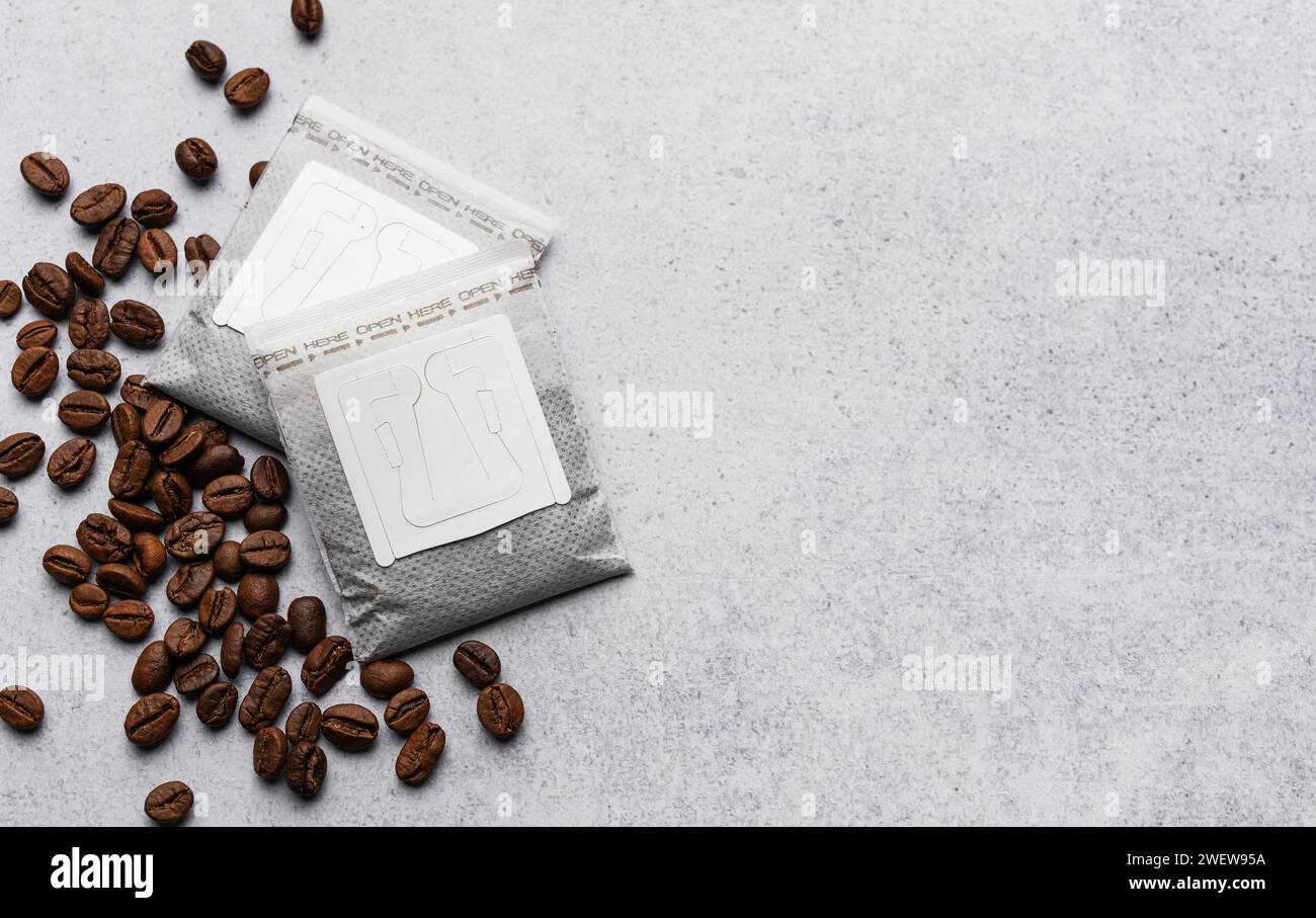 Versare i sacchetti di carta del caffè con i chicchi di caffè su uno sfondo grigio di cemento Foto Stock