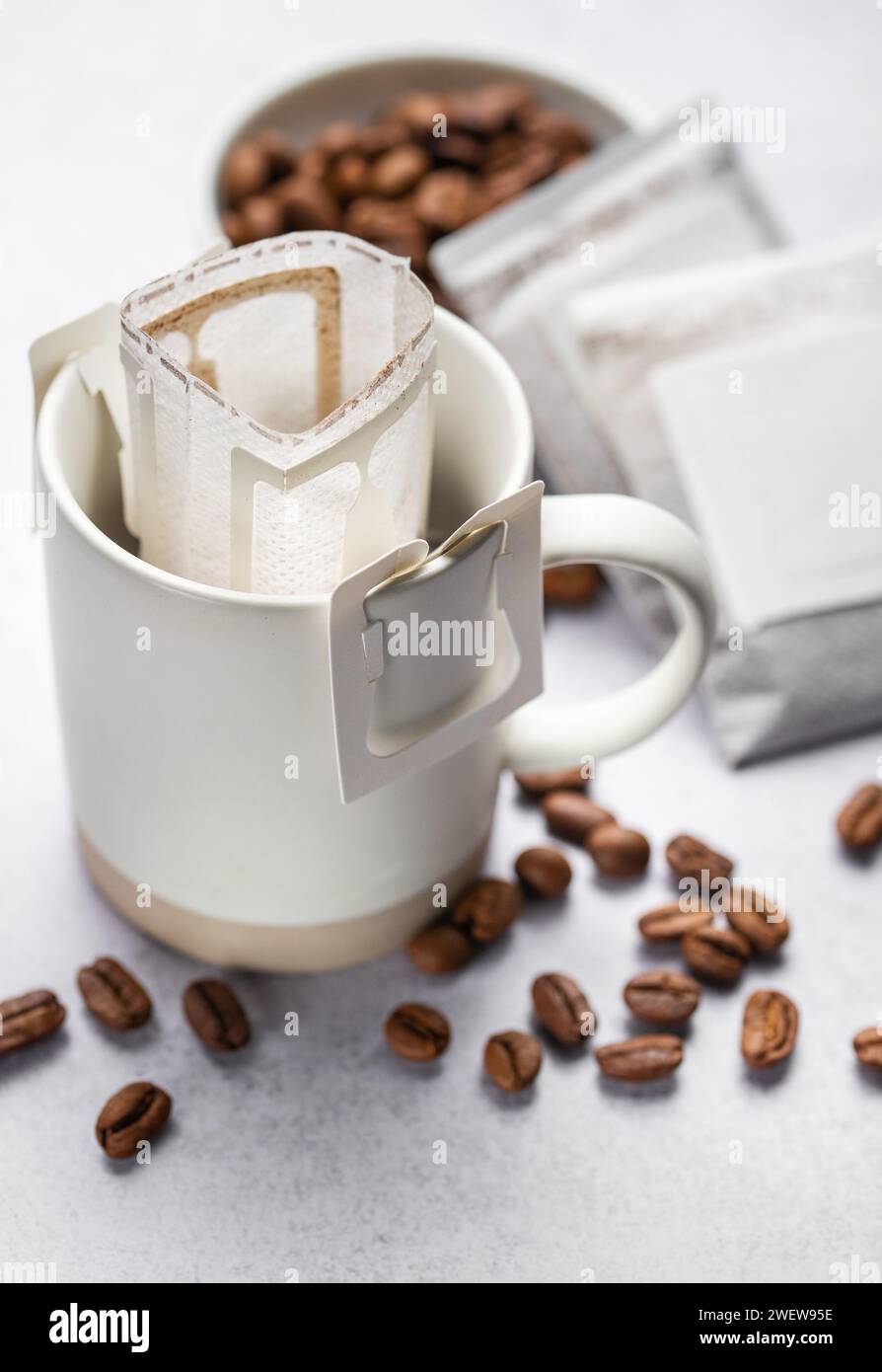 Una tazza di caffè gocciolante appena fatto. Versare il sacchetto del caffè con il caffè macinato per l'erogazione in una tazza Foto Stock