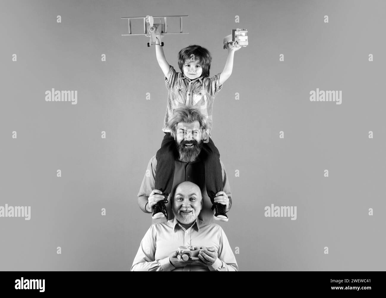 Figlio con padre e nonno. Famiglia uomo vacanza e convivenza. Uomini generazioni. Bambino felice che gioca con i giocattoli su sfondo giallo. Foto Stock