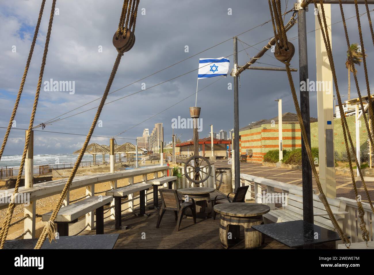 Pilastro con una ruota di legno e la bandiera israeliana in mare con il tempo tempestoso Foto Stock