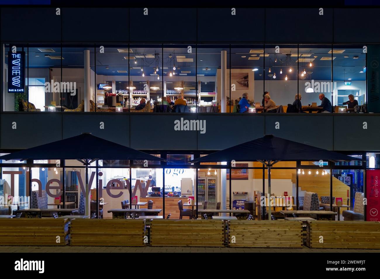 Teignmouth, Devon. Il Pavilion Cafe e bar si trova su un alto edificio a due piani con i commensali all'interno. Fotografia notturna con edificio illuminato all'interno. Foto Stock