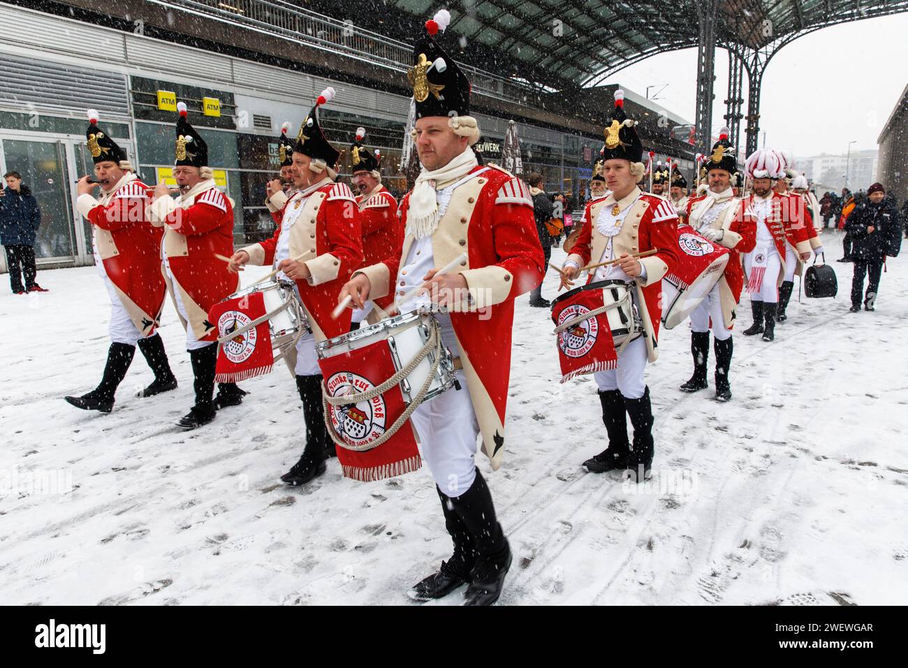 Banda di marcia della Rote Funken (una società di carnevale) su Breslauer Platz di fronte alla stazione centrale, inverno, neve, Colonia, Germania. Spielmannszu Foto Stock