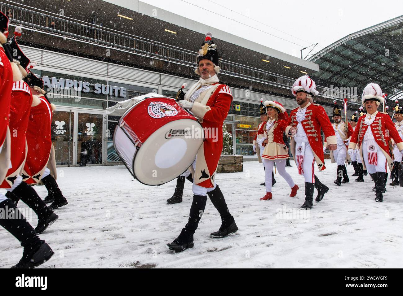 Banda di marcia della Rote Funken (una società di carnevale) su Breslauer Platz di fronte alla stazione centrale, inverno, neve, Colonia, Germania. Spielmannszu Foto Stock