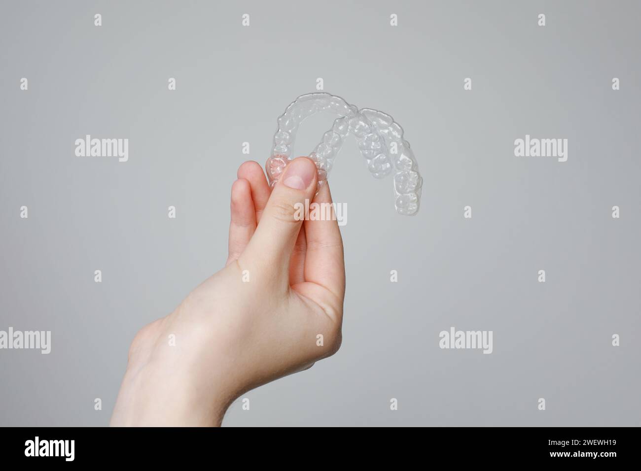Mano umana con allineatori odontoiatrici invisibili trasparenti o bretelle applicabili al trattamento ortodontico Foto Stock