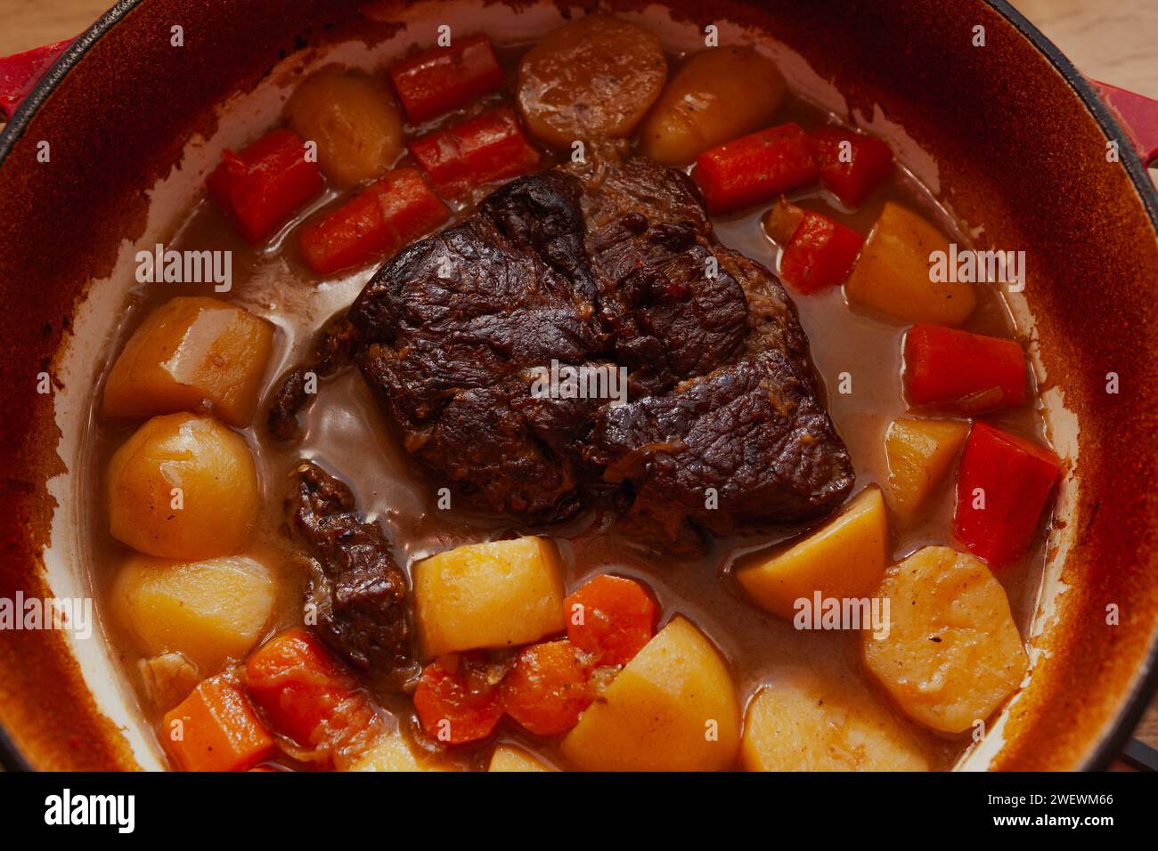 Arrosto con carote e patate cotte lentamente nel forno rosso olandese, vista dall'alto Foto Stock