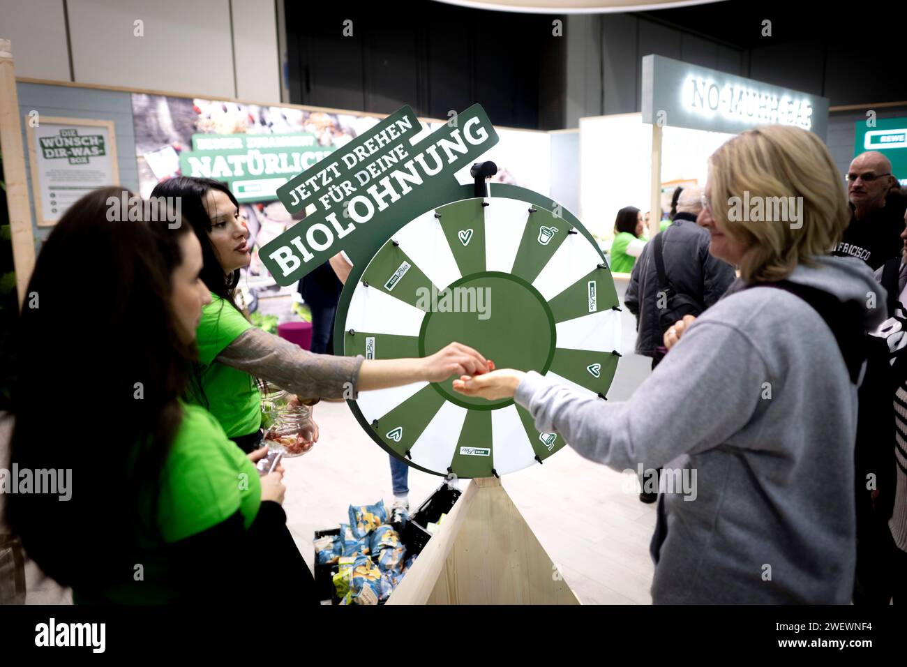 Gruene Woche Berlin DEU, Deutschland, Germania, Berlino, 23.01.2024 Besucher und Aussteller von Rewe bei einem Glueckspiel zum Thema oekologische Landwirtschaft in der Biohalle vom Forum moderne Landwirtschaft auf der Messe der Internationalen Gruenen Woche unter dem motto Moege die Vielfalt MIT Euch sein Berlin Deutschland. Die Internationale Gruene Woche Berlin ist eine internationale Verbrauchermesse und Ausstellung der Ernaehrungswirtschaft, Landwirtschaft, Gartenbau und fuer landwirtschaftliche Produkte aus aller Welt. Grüne Woche en: Visitatori ed espositori di Rewe a un gioco di chanc Foto Stock