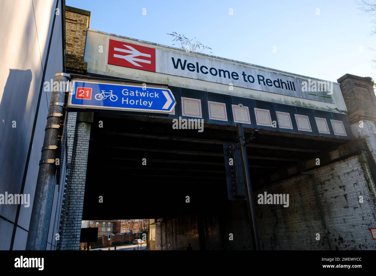 Il ponte ferroviario accanto alla stazione ferroviaria di Redhill, Surrey, con il cartello Welcome to Redhill e il logo della ferrovia britannica che mostra le piste stradali e ciclabili della A25. Foto Stock