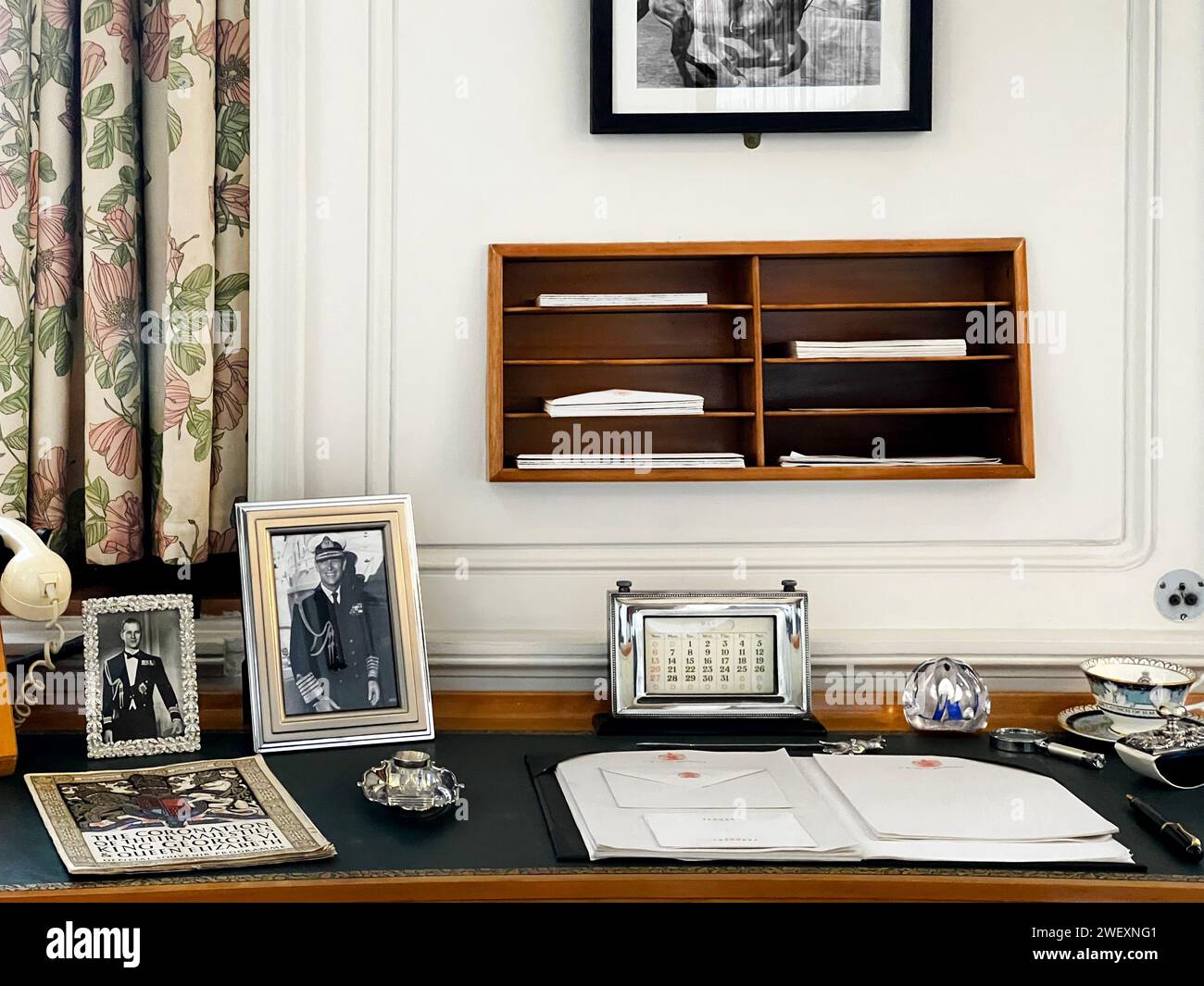 Primo piano della scrivania dell'ufficio della Regina Eliabeth con cornice, foto, calendario, tazza da tè e cancelleria a bordo, Her Majesty's Yacht Britannia Foto Stock