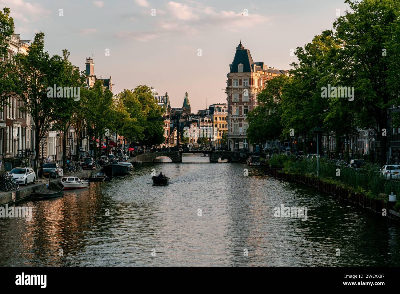 Calma serale sui canali di Amsterdam: Un aggraziato connubio di architettura storica e una piacevole navigazione in barca Foto Stock