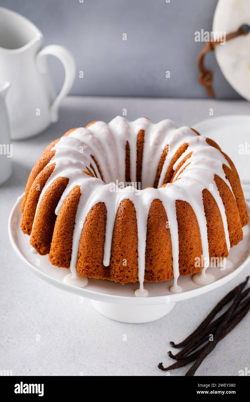 Torta in bundle alla vaniglia con glassa di zucchero in polvere che gocciola su un supporto per torta Foto Stock