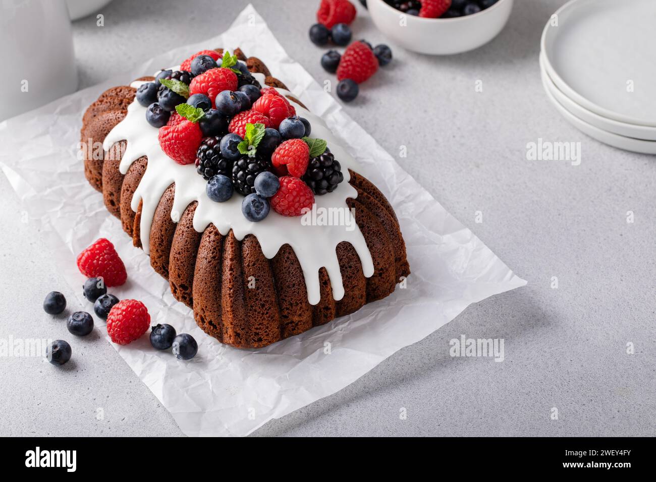 Torta al cioccolato con glassa alla vaniglia e frutti di bosco freschi sulla parte superiore, un'idea complessa di torta al pane Foto Stock