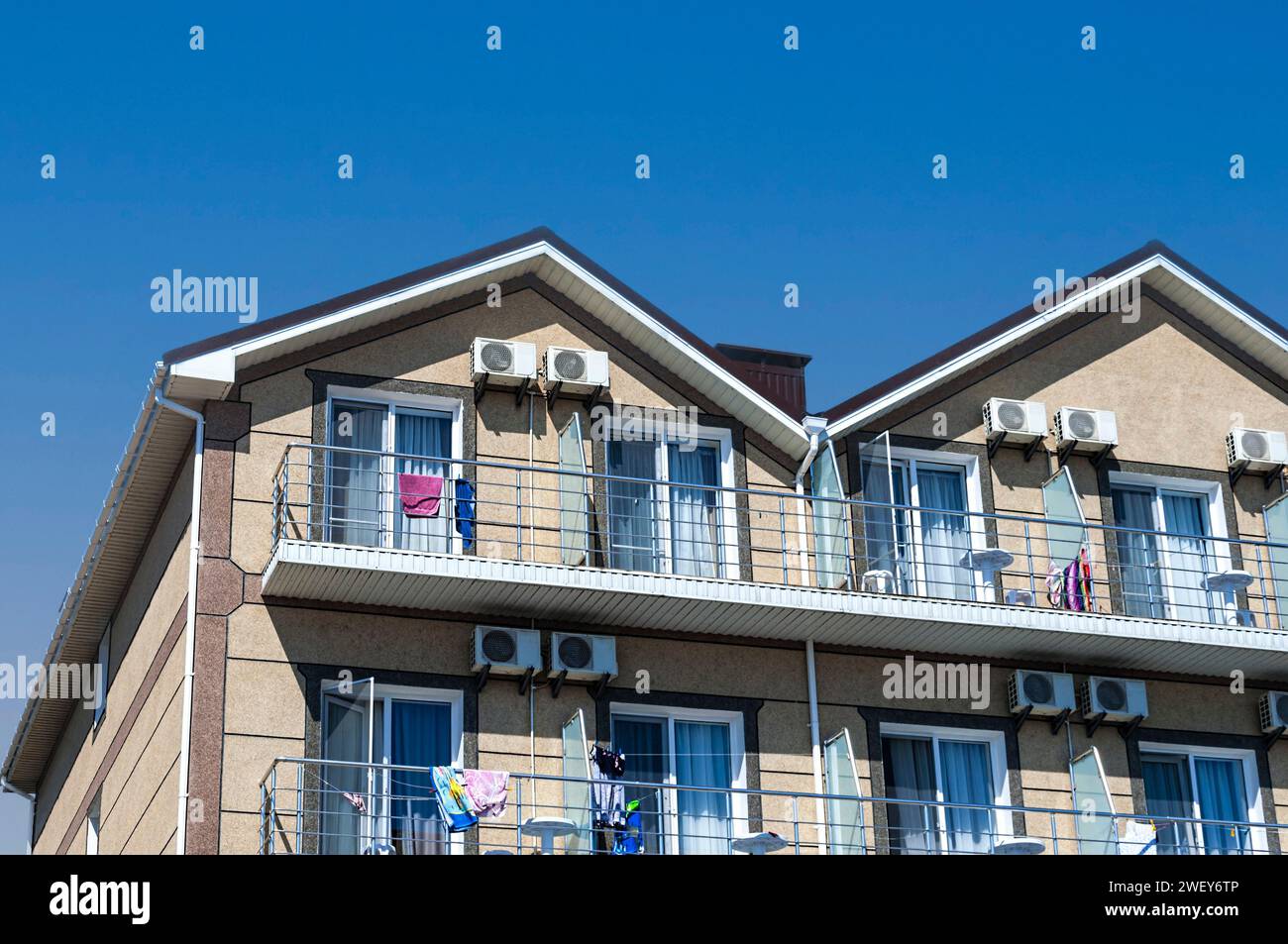 La parte superiore della facciata di una casa a due piani di colore beige contro un cielo blu. Foto Stock