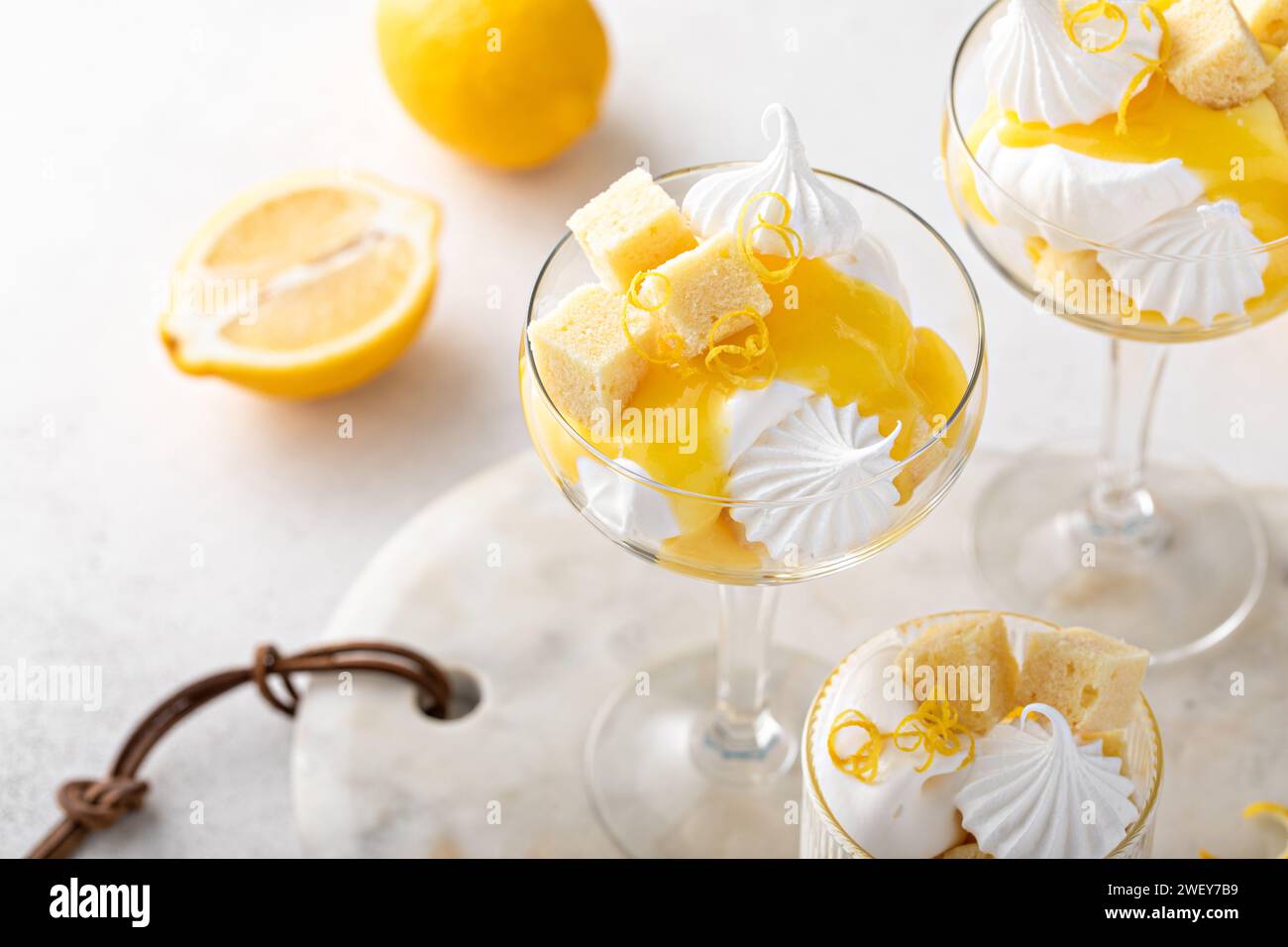 Trifle al limone con torta libbre, cagliata al limone, panna montata e meringa in bicchieri coupé Foto Stock