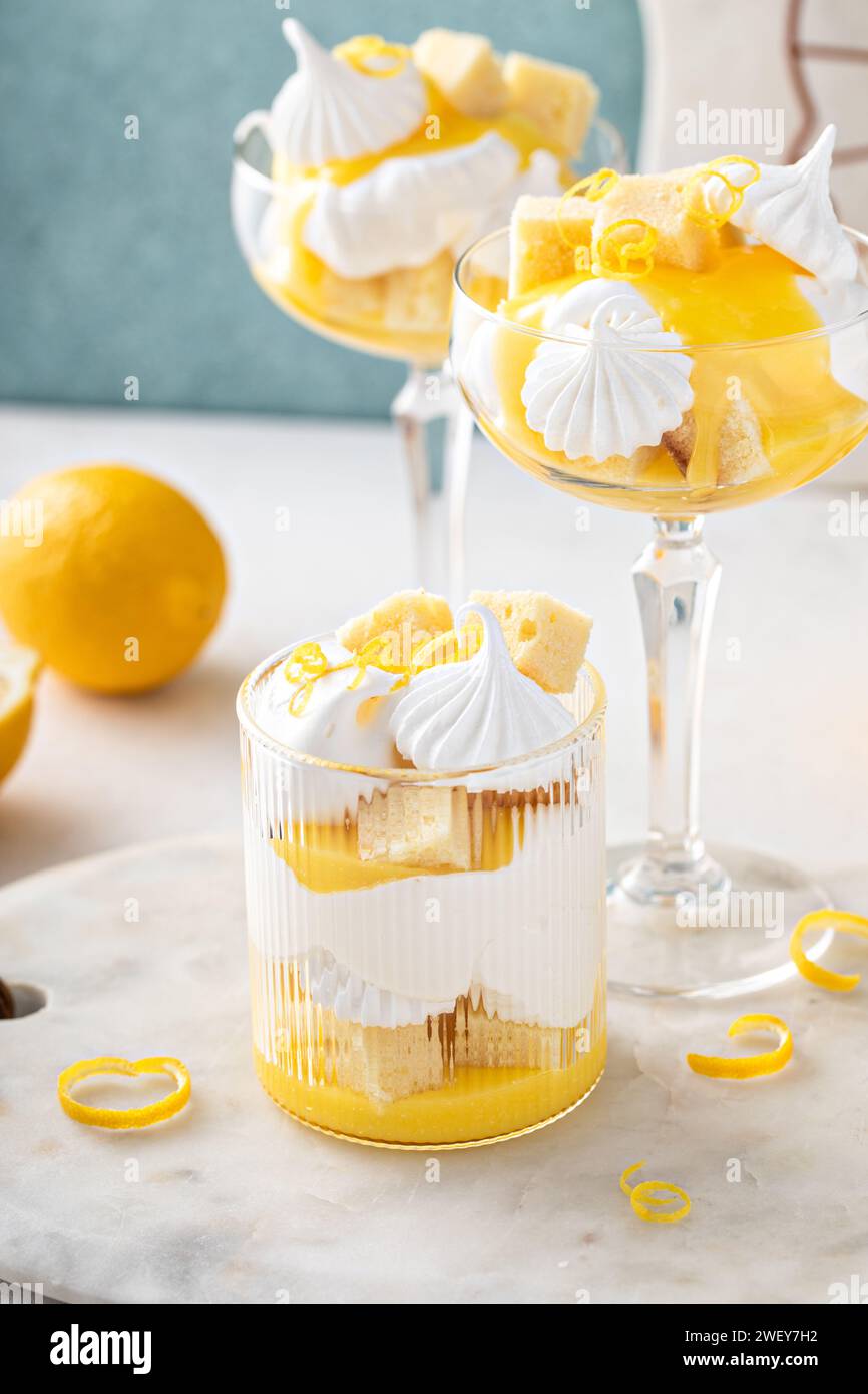 Trifle al limone con torta libbre, cagliata al limone, panna montata e meringa in bicchieri coupé Foto Stock
