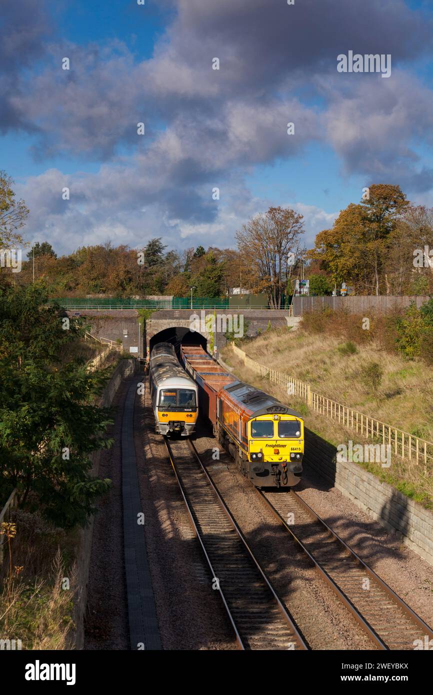 Locomotiva Freightliner classe 66 con un treno merci vuoto di vagoni scatolati che passa una classe 165 della Chiltern Railways presso il tunnel Wolvercote, Oxford, Regno Unito Foto Stock