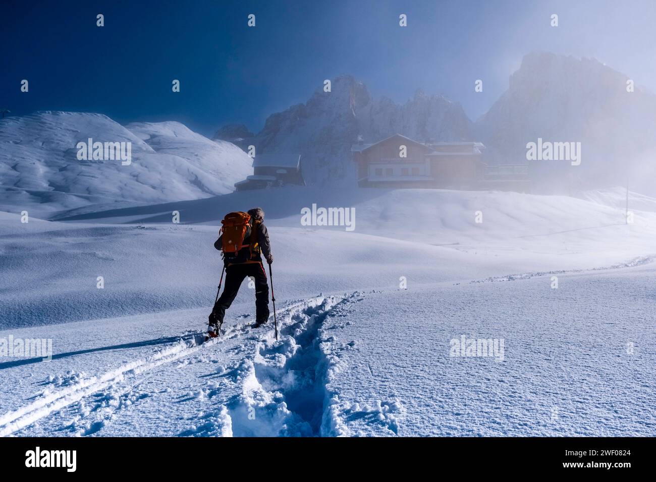 Scialpinismo che si snoda fino al rifugio Baita Segantini attraverso la nebbia, le cime del gruppo pale in lontananza, in inverno. San Martino di Castroz Foto Stock